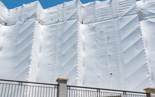 View,Of,Building,With,Scaffolding,Covered,With,White,Scaffold,Mesh